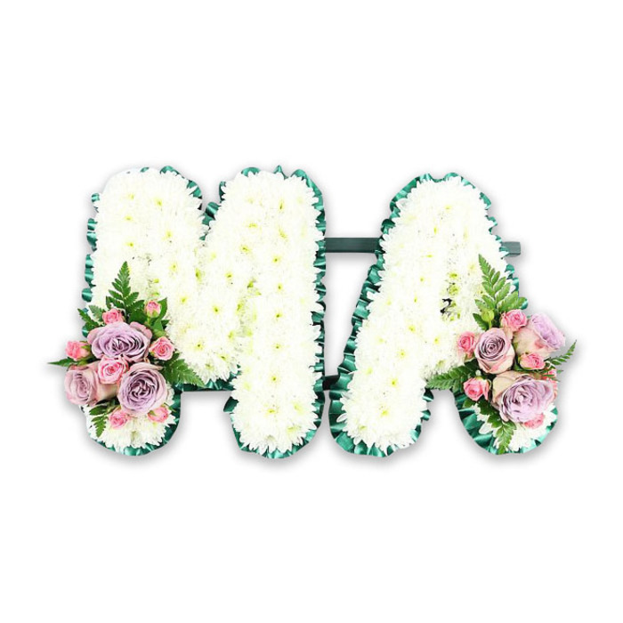 A refined and heartfelt floral memorial spelling MA is captured here as if ready to be placed gently beside a coffin or at the front of a chapel in South Woodford. Each letter stands upright, clearly defined and meticulously covered in pristine white chrysanthemums. The individual blooms, with their many small, feathery petals, are arranged so closely that the surface of both letters appears plush and padded, like a soft quilt made entirely of flowers. The whiteness of the chrysanthemums symbolises innocence and peace, providing a calm, unbroken canvas on which the message of love is quietly written. Framing this sea of white is a deep green satin ribbon, folded into delicate pleats and following every curve and angle of the M and the A. This ribbon border introduces a rich, natural contrast that echoes the greenery of nearby Wanstead Park, while also giving the tribute a tailored, professional finish suited to a formal funeral setting. At the lower left corner of the M and the lower right corner of the A, two identical accents of colour soften the composition. These are compact bouquets of pastel roses: soft-pink blooms, lilac or muted purple roses, and smaller pink spray roses that add texture and depth. Their petals spiral gently outwards, some just beginning to open, suggesting ongoing love and memory. Slender fern fronds and a touch of fresh foliage extend from each cluster, breaking the outline slightly and adding a natural, garden-inspired movement. Set against a pure white background, with no distractions, this funeral letter tribute feels both intimate and dignified-a personal way for a South Woodford family to say goodbye to their mum, mummy, or mama with flowers that speak when words are hard to find.