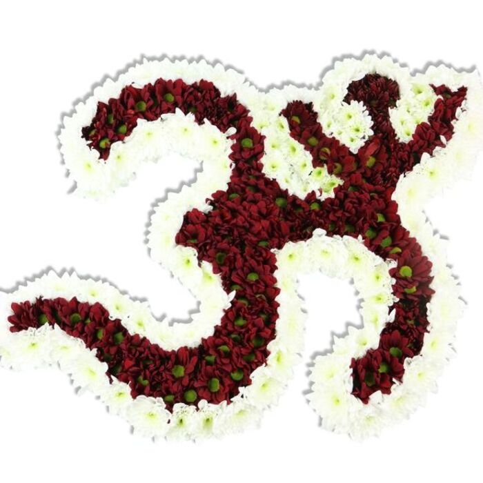 A meticulously crafted floral Om (Aum) symbol, composed of a compact mass of dark red to maroon chrysanthemum-style blooms, is presented against a stark white background that amplifies its sculptural form. The primary strokes of the symbol-its looping '3' shape, the curved descending stroke, and the crescent-and-dot at the top-are densely filled with those deep red flowers, many of which reveal small lime-green centres that add a subtle, botanical fleck of contrast. Encircling and defining the interior negative spaces is a generous border of snow-white spray chrysanthemums; their bright petals create a clean, graphic outline that transforms the cluster of blooms into a recognisable and dignified emblem. The flowers are arranged so closely together that the surface reads as a soft, tactile plane of petals, and a faint shadow cast below gives the composition a gentle lift from the white plane. The image conveys quiet solemnity and ritual beauty-perfect for memorial services, temple offerings, or cultural ceremonies where the symbol's spiritual meaning is central. From the perspective of a South Woodford florist, this would be the kind of carefully assembled tribute ordered for a remembrance laid out in a local community centre off George Lane or for a ceremonial event near the Roding; it speaks to both religious reverence and meticulous floral craft, offering a tangible focal point for prayer, remembrance, and cultural observance.