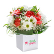 Brimming with joyful vitality, this flower arrangement-prepared with care by the expert florists of South Woodford-gleams against a backdrop of serene white. At its core, a medley of coral, peach, and red carnations unfold their signature ruffled petals, each one lush and inviting, exuding the warmth of a sunrise along George Lane. Interspersed among these are snowy white daisies with vibrant, sunny-green centres, infusing the bouquet with a breezy playfulness and uplifting spirit found in the gardens around South Woodford. Ethereal clusters of white baby's breath waltz between the blossoms, lending a softness that calls to mind a gentle morning mist. Only a keen eye will spot the unopened buds tinged with purple, discreetly tucked into the mix and suggesting that life-and beauty-is forever unfolding anew. Broad, glossy green leaves fan outward, enclosing the flowers in a cradle of natural elegance inspired by the leafy avenues near Hermon Hill. Resting in a minimalist, square white bag with sturdy ribbon handles, the bouquet is ready to brighten any doorstep near Epping Forest or mark a cherished occasion with sincerity and style. Each element is placed with attentive skill to create a mood of uplifting celebration and thoughtful intention-perfect for birthdays, milestones, or spontaneous gestures of affection in South Woodford.