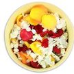 From a bird's-eye view, a softly rounded pale yellow ceramic bowl is shown overflowing with a rich mixture of loose petals, thoughtfully arranged as a gentle funeral tribute. Deep crimson rose petals dominate, their velvety surfaces folding and overlapping to form a lush, almost quilt-like layer that conveys profound affection and remembrance. Between these darker notes, clusters of vivid yellow and tender peach-apricot rose petals brighten the composition, their softly curved shapes catching the light and suggesting hope, gratitude, and the warmth of shared stories. Threaded throughout the bowl are many tiny white florets, likely hydrangea or a similar delicate bloom, scattered like small stars against a twilight sky, bringing an air of purity and serenity. The petals appear to have been placed with care yet left slightly loose, creating natural dips, ridges, and pockets of shadow that give the bowl a relaxed, organic feel, as if petals were freshly gathered after a farewell ceremony in one of South Woodford's peaceful churches. You can almost sense a gentle, layered fragrance rising from the bowl-a blend of classic rose sweetness and light, fresh blossom-calming and reflective rather than intense. This arrangement carries an intimate scale, perfect for setting on a bedside table in a hospice room, placing near a framed photograph at a memorial, or resting on a console table in a South Woodford home where family and friends can pause in quiet thought. It is a simple yet eloquent floral expression of sympathy, crafted to honour a life with colour, softness, and understated grace.