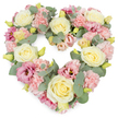 A romantic, heart-shaped funeral wreath fills the image, its dense blanket of flowers arranged with a careful, loving touch. Against a bright white background, the soft tones of cream, pink, and green appear especially gentle, inviting the eye to trace the heart's outline. Creamy ivory and pale yellow roses are placed as the main focal blooms, their rounded, velvety petals layered in generous spirals, bringing a sense of calm and stability to the tribute. Between and around them, clusters of delicate pastel pink carnations create a plush, textured surface, their frilled petals nestling together until the underlying base is completely hidden. Intertwined with these are deeper pink and mauve lisianthus flowers, some fully open with softly rippling petals, others still slightly budded, adding a more relaxed, natural note to the arrangement. Sprays of silvery eucalyptus weave in and out, their rounded, muted green leaves following the curve of the heart and lending a cool, serene tone that balances the warmth of the roses and carnations. Small, yellowish-green buds appear here and there, like quiet signs of new beginnings. The result is a full, luxurious heart design that speaks of affection, remembrance, and compassion. This type of floral tribute would feel at home at a South Woodford funeral or memorial gathering, perhaps travelling from a local florist's studio near George Lane to a family service or resting place. Its gentle colours and thoughtful composition offer solace and convey sympathy with dignity, making it a meaningful choice when saying goodbye to someone dearly loved.