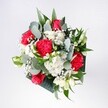 A hand-tied bouquet of red and pink roses, velvety crimson carnations, and snow-white daisies is captured in soft, natural light, looking as if it has just been placed on a kitchen table in a South Woodford home. The roses form the confident heart of the design, their petals rich and layered, while the carnations add ruffled, almost feathery folds of deep red and rosy pink that seem to ripple outward with energy. Between them, clusters of tiny white daisy-like chrysanthemums and airy gypsophila glow like little lanterns, lifting the whole arrangement with a bright, joyful lightness. Cool eucalyptus leaves curve gracefully around the blooms, their silvery green tones and slightly matte texture contrasting with the gloss of the tropical greenery that frames the bouquet. The foliage creates a neat, modern outline, giving structure without feeling stiff or formal. Seen from above, every flower seems to have its own breathing space, creating an impression of balance and ease, as if the bouquet were captured in a quiet pause before guests arrive. The mood is cheerful and optimistic, perfect for celebrating a birthday, a promotion, or the simple happiness of having fresh flowers delivered from a local South Woodford florist. One can almost imagine the scent: the warm spice of carnations, the soft sweetness of roses, and the fresh, resinous note of eucalyptus, combining into a gentle fragrance that would brighten a hallway near George Lane or bring a touch of celebration to a flat overlooking the leafy paths around Eagle Pond. This bouquet feels like a bright morning you can hold in your hands, full of promise, affection, and the calm excitement of a special day beginning.